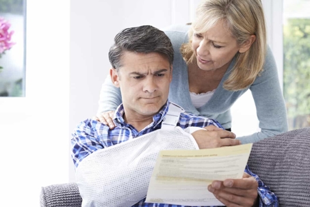 Injured man looking at paperwork with his wife.